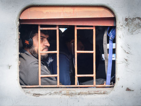 Sambhar, India - February 05, 2019: Indian man in headphones is sitting in train, and looking...