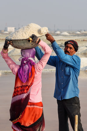 Sambhar, India - February 04, 2019: Indian workers putting basin with salt on head of woman on Sambhar Salt Lake. Rajasthanのeditorial素材