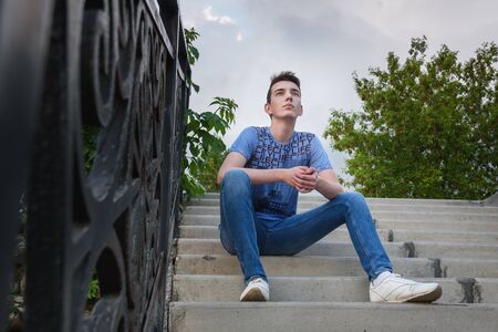 Teenage boy on the stairs on the street in summerの写真素材
