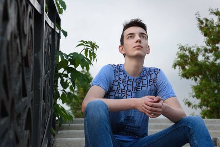 Teenage boy on the stairs on the street in summer