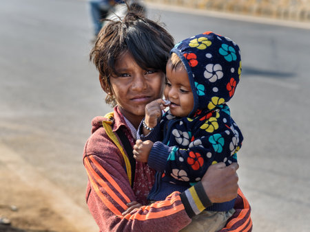Ajmer, India - February 07, 2019: Indian boy with child on the street. Poor people come with family to the city from the village for work. And they living in the street in tent home. Rajasthanのeditorial素材