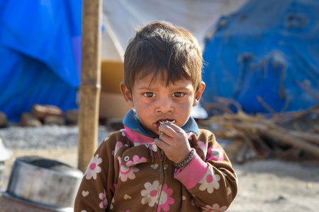Ajmer, India - February 07, 2019: Portrait of Indian boy on the street. Poor people come with family to the city from the village for work. And they living in the street in tent home. Rajasthanのeditorial素材