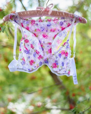 White with flower print hanging on hanger on nature backgroundの写真素材