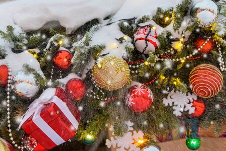 Christmas trees decorated with balls and lights, garlands covered with snow in the eveningの写真素材