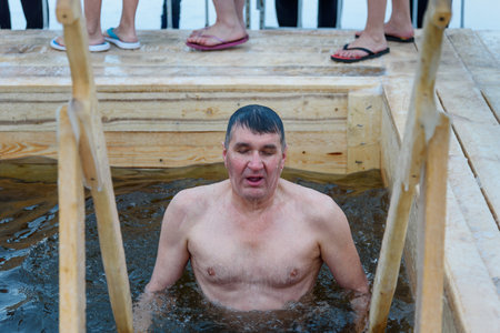 Nizhny Tagil, Russia - January 19, 2019: Man bathes into cold water of ice-hole on Epiphany day. Traditional ice swimming in Orthodox church Holy Epiphany Dayのeditorial素材