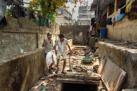 Mumbai, India - February 26, 2019: Indian men cleaning gutter in Dharavi Slum at Mumbaiのeditorial素材