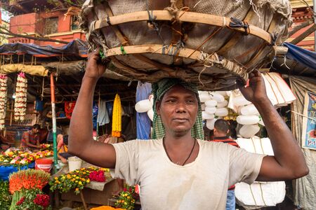 Kolkata, India - March 12, 2019: Indian man carrying flower basket on head in Flower market at...
