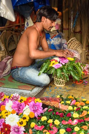 Kolkata, India - March 11, 2019: Indian seller makes basket of flowers on Flower market at Mallick Ghat in Kolkataのeditorial素材