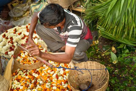 Kolkata, India - March 11, 2019: Indian seller weighs flowers by scales on Flower market at Mallick Ghat in Kolkataのeditorial素材