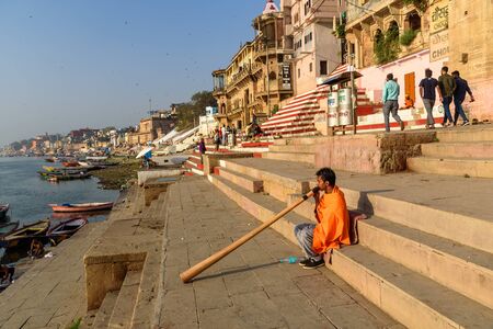 Varanasi, India - March 16, 2019: Man playing Didgeridoo on ganga river bank in morning
