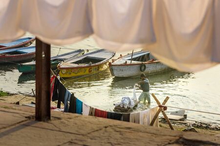 Varanasi, India - March 18, 2019: Indian man washing clothes in holy water of river Ganga in the morningのeditorial素材