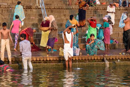Varanasi, India - March 18, 2019: People bathing in water holy Ganga river at Kedar Ghat in morning