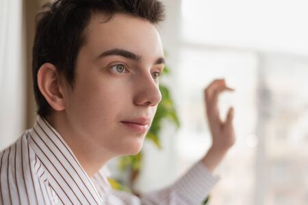 Portrait of pensive guy looking out window at home