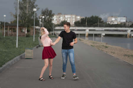 Young couple holding hands and smiling while walking through the city streetの写真素材
