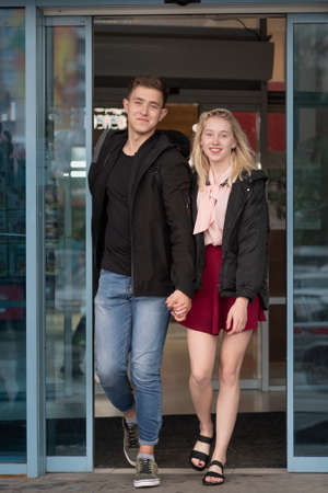 Happy young couple holding hands leaving shopping mall