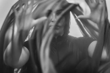 Portrait of woman under transparent textile. Black and whiteの写真素材