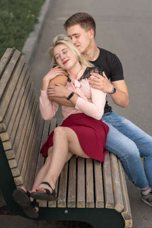 Young couple kissing at the bench on the street in summerの写真素材