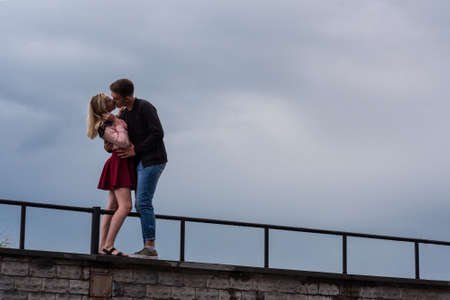 Beautiful loving each other couple is standing and kissing on on dramatic sky backgroundsの写真素材