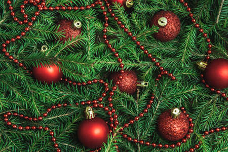 Background of Christmas tree branches with red baubles and beads. Nature New Year textureの写真素材