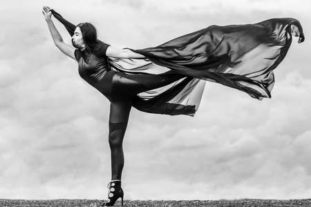 Woman in black overalls dancing with flying fabric outdoors. Black and whiteの写真素材