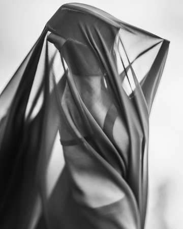 Closeup detail leg in high heeled strips shoe of woman under black transparent textile. Black and whiteの写真素材