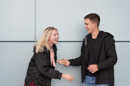 Happy young couple standing near gray wall in the streetの写真素材