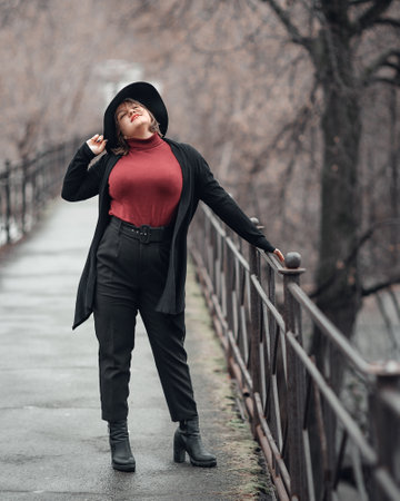 Brunette girl in hat on the bridge in cit in autumn. Plus size modelの写真素材