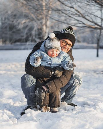 Young father and little boy playing together in park in winter dayの写真素材