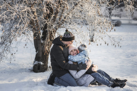 Happy family hugging together near tree in winter parkの写真素材