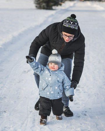 Happy family father and son walking together in winter parkの写真素材