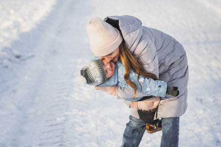 Young mother and little boy playing together in park in winter dayの写真素材