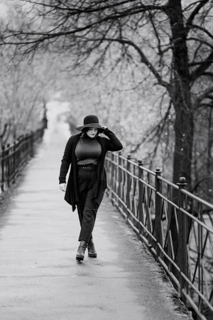 Brunette girl in hat on the bridge in cit in autumn .. Plus size model. Black and whiteの写真素材