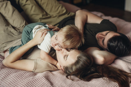 Happy family with little son lying and playing on bed at home. Soft focusの写真素材