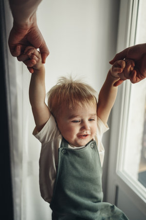 Fathers hands pull happy son up by hands at home. Top wiev. soft focusの写真素材