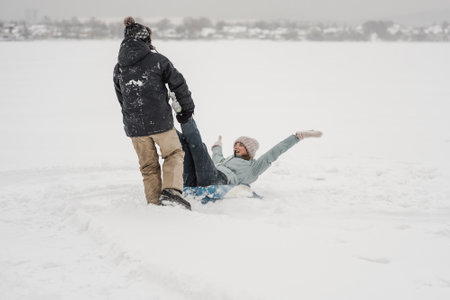Man pulling snow tube with girlfriend. Young happy couple walking in the street in winter dayの写真素材
