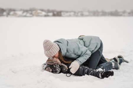 Loving guy and girl are lying in the snow. Young happy couple walking in winter dayの写真素材