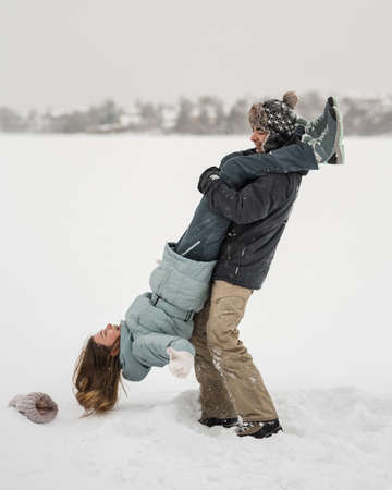 Young happy couple walking in winter day. Woman on man's shoulder by legsの写真素材