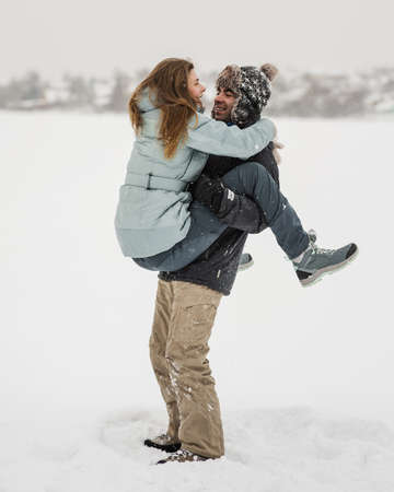Young happy couple walking in winter day. Man lifting his womanの写真素材
