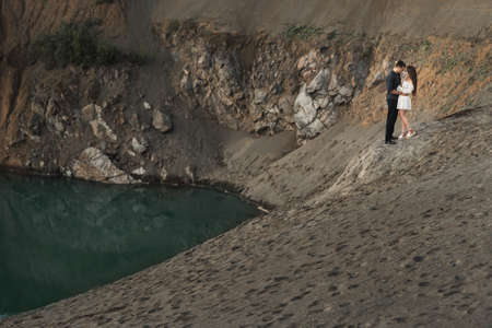 Young man and girl are higging on the bank of lake in nature. Couple in love spend time forever togetherの写真素材