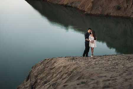 Young man and girl are higging on the bank of lake in nature. Couple in love spend time forever togetherの写真素材