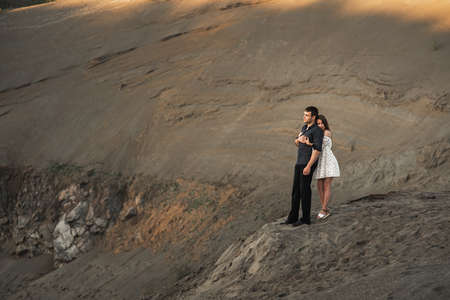 Young man and girl are higging on the bank of lake in nature. Couple in love spend time forever togetherの写真素材