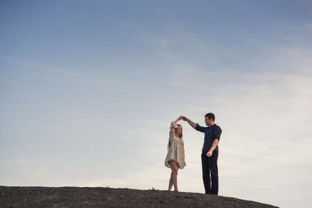 Happy couple dancing outdoors at summertime under blue sky in the eveningの写真素材