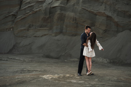 Happy couple dancing and kissinc outdoors at summertime on gray sand backgroundの写真素材