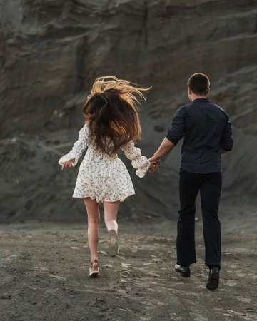 Couple of lovers holding hands and running away in sunny dayの写真素材
