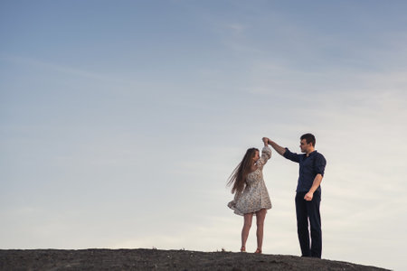 Happy couple dancing outdoors at summertime under blue sky in the eveningの写真素材