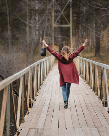Young happy woman walking with ukulele guitar in bridge in autumn forestの写真素材