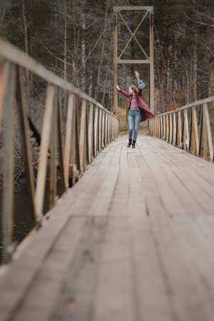 Young happy woman walking with ukulele guitar in bridge in autumn forestの写真素材