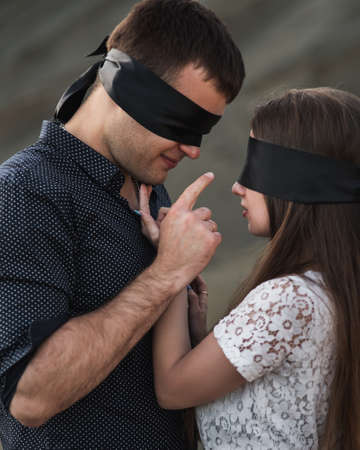 Romantic couple blindfolded with black ribbon touching each other. Love blind conceptの写真素材