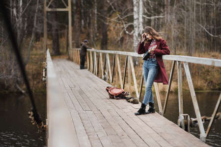 Young woman walking and playing ukulele guitar in bridge in autumn forestの写真素材