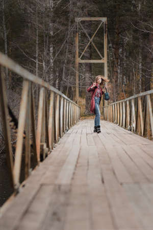 Young happy woman walking with ukulele guitar in bridge in autumn forestの写真素材